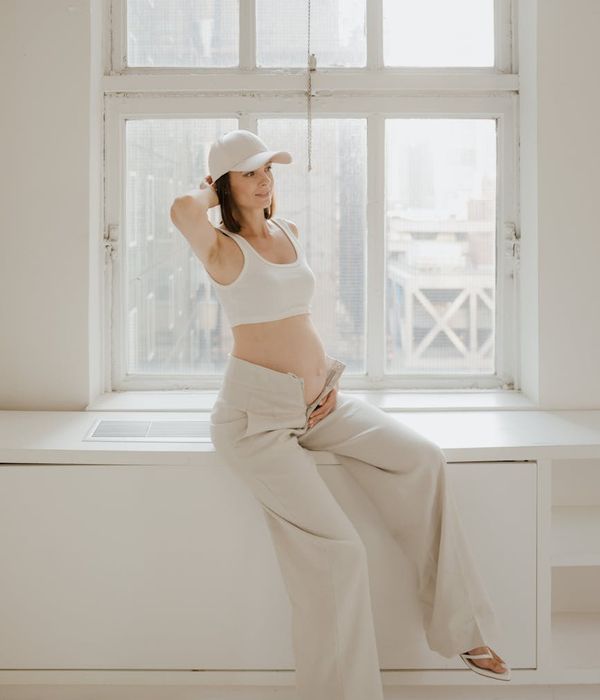 Pregnant woman in a peaceful yoga pose in a bright room.