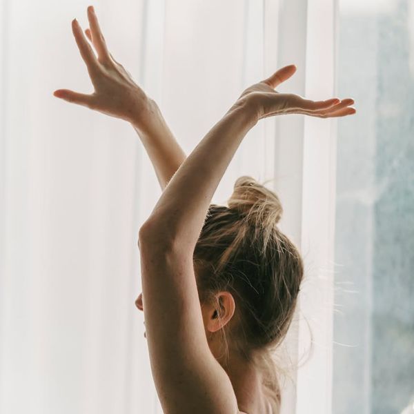 Silhouette of a person in a gentle yoga warrior pose.